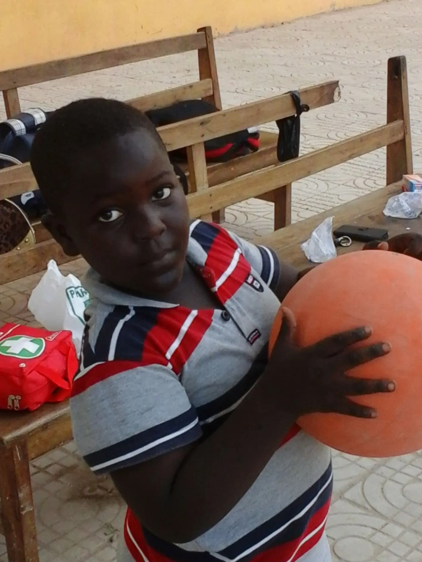A boy holds the ball and looks straight at the camera · Accra, 5 April 2014